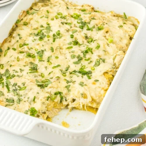 Closeup of the casserole in a dish with a serving removed to show the layers of tortillas, chicken, and cheese.