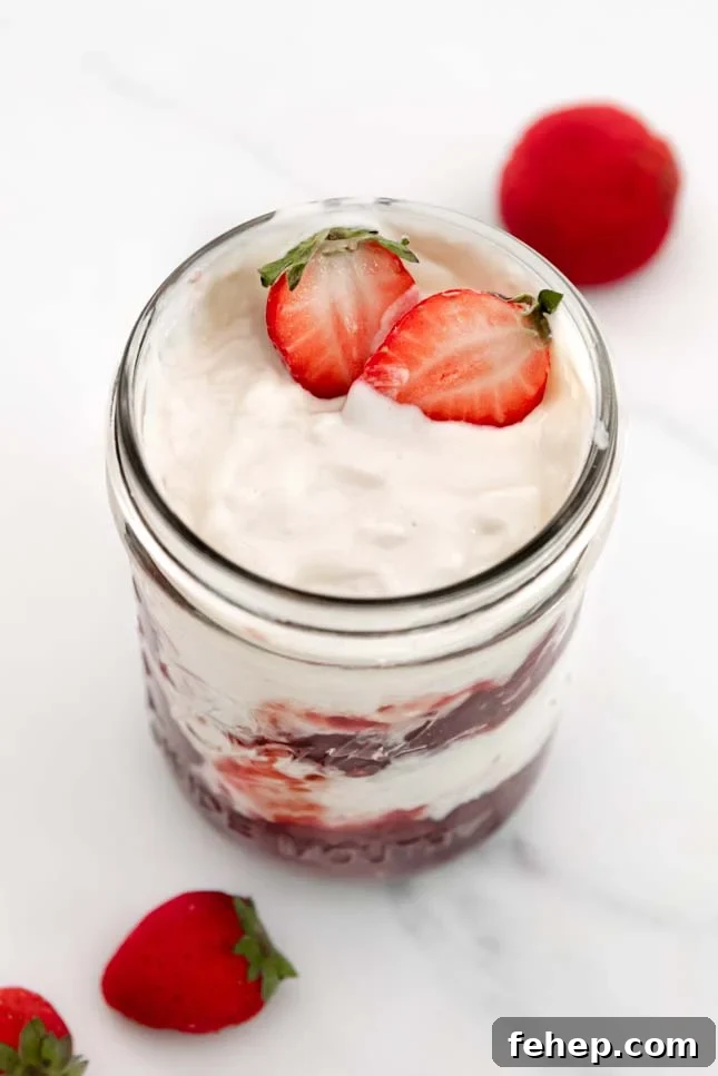 Photo of a glass jar of coconut yogurt with some strawberries