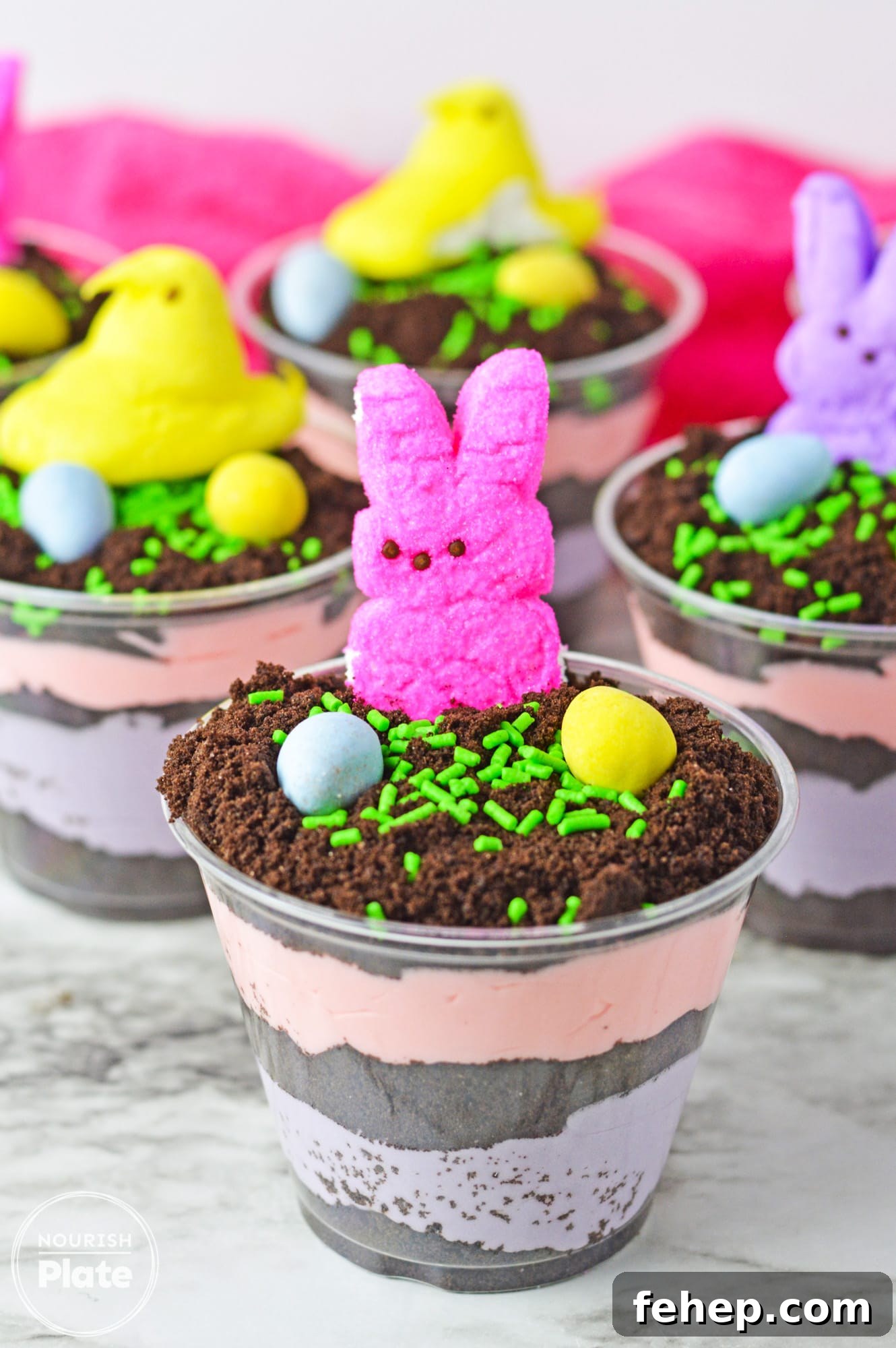Easter Dirt Cups Dessert Recipe — Fun No-Bake Treats for Kids 2 Easter dirt cups with layered instant pudding in colors, topped with peeps and mini eggs.