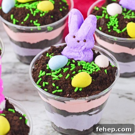 Easter Dirt Cups Dessert Recipe — Fun No-Bake Treats for Kids 7 Easter dirt cups with layered instant pudding in colors, topped with peeps and mini eggs.