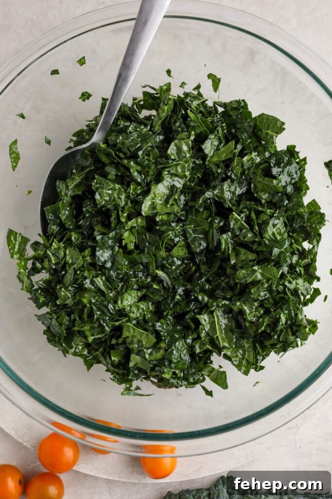 shredded kale massage with olive oil with a spoon with cherry tomatoes on the side