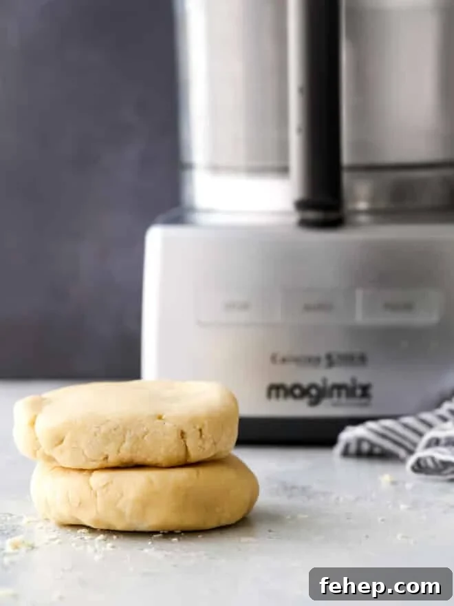 pie crust disks stacked in front of a food processor