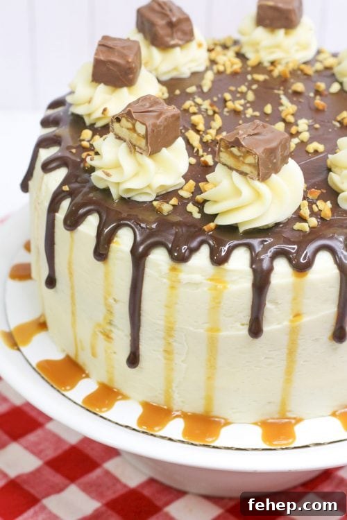 Decadent Snickers Layer Cake Recipe for Chocolate Peanut Lovers 4 a snickers cake with caramel buttercream topped with snickers bars and peanuts.