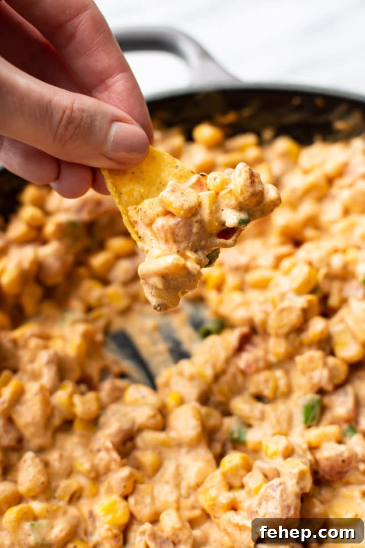 Cream Cheese Corn Dip Recipe for Parties and Game Day 3 cream cheese corn dip in a skillet being scooped out with a tortilla chip