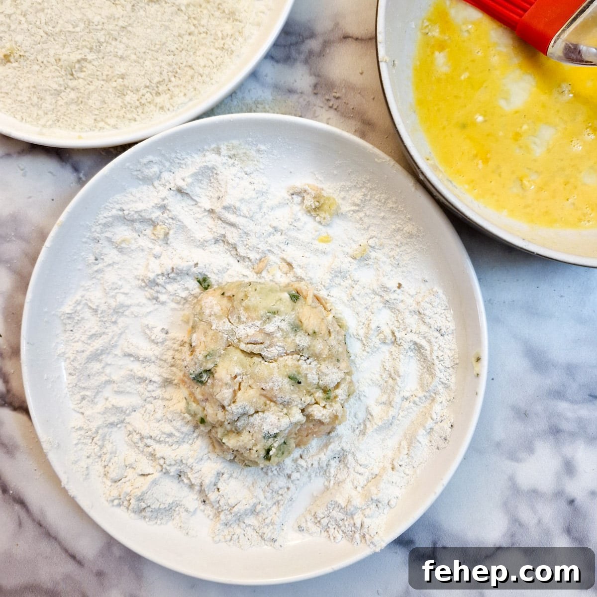 Crispy Salmon Fish Cakes with Lemon-Dill Sauce 11 A fish patty in a bowl of flour.