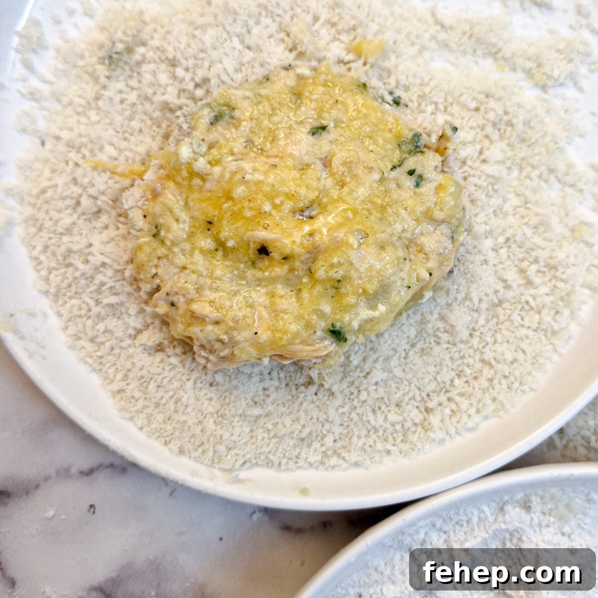 Crispy Salmon Fish Cakes with Lemon-Dill Sauce 12 A fish patty in a bowl of breadcrumbs, brushed with beaten egg.