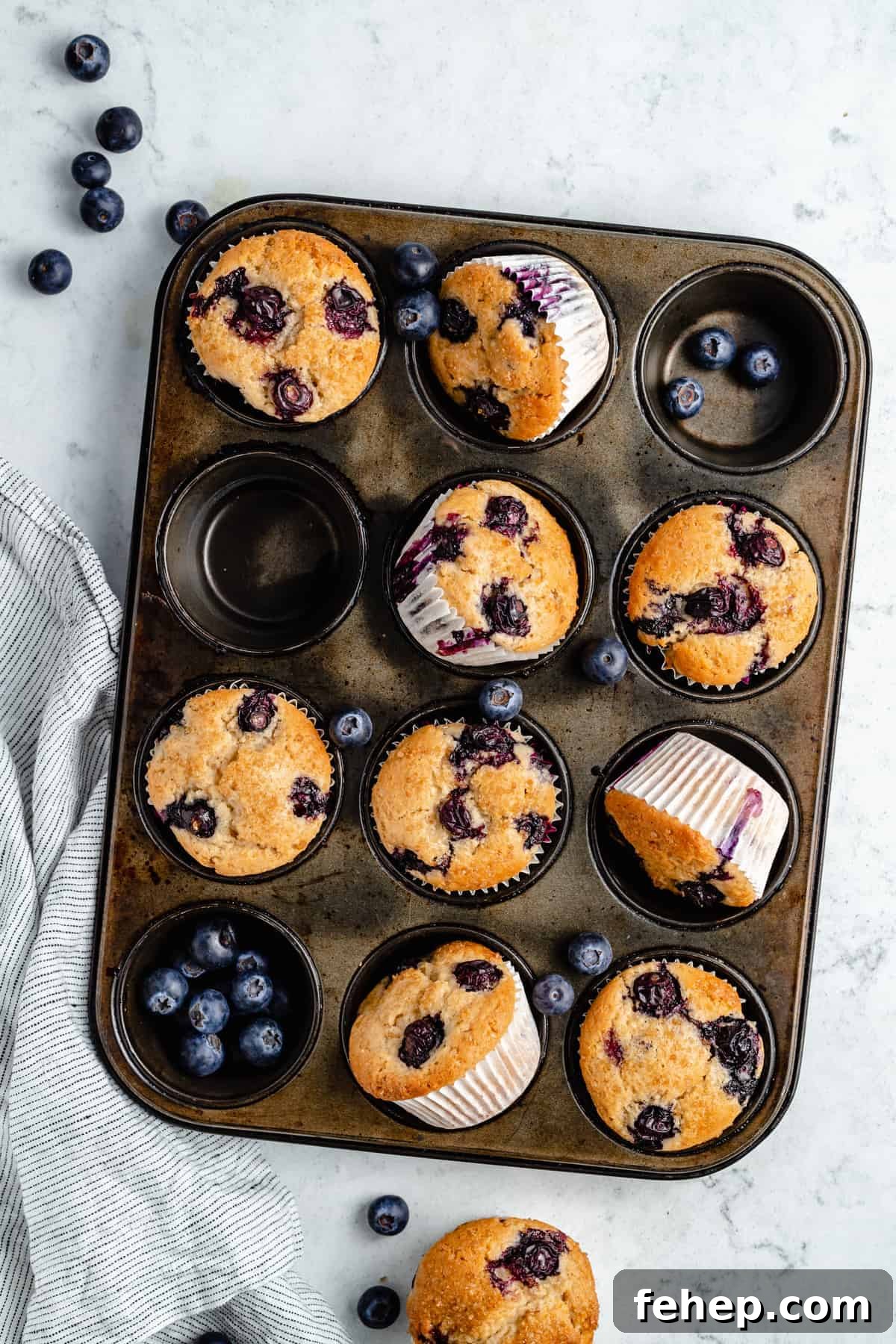 Vegan Blueberry Muffins Recipe for Moist, Fluffy Results 3 Blueberry muffins and blueberries in a muffin pan.