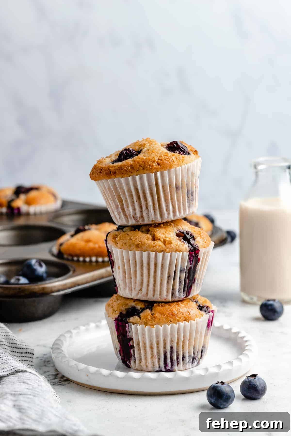 Vegan Blueberry Muffins Recipe for Moist, Fluffy Results 5 Three stacked blueberry muffins on a plate.