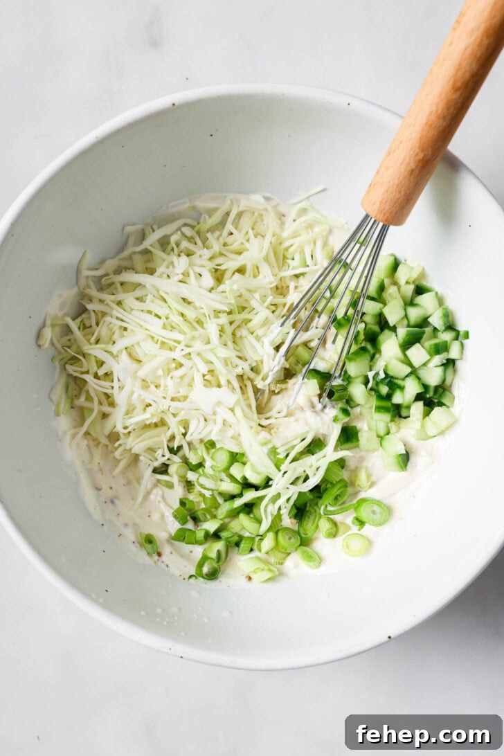 Creamy Chicken Mayo Sandwich Recipe for Balanced Flavor 11 Chopped cabbage, green onions and cucumbers in a bowl with a whisk.