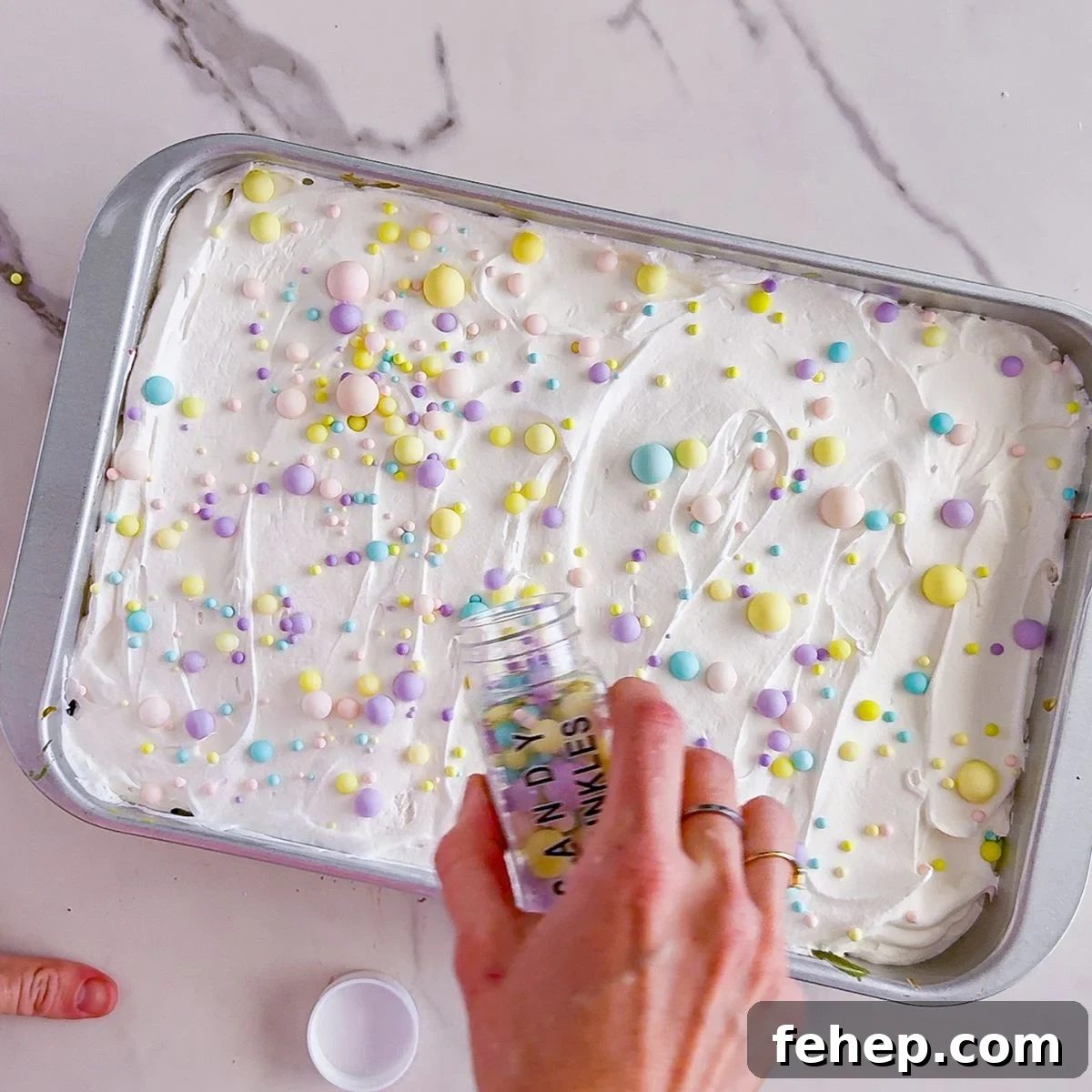 Adding sprinkles to poke cake.