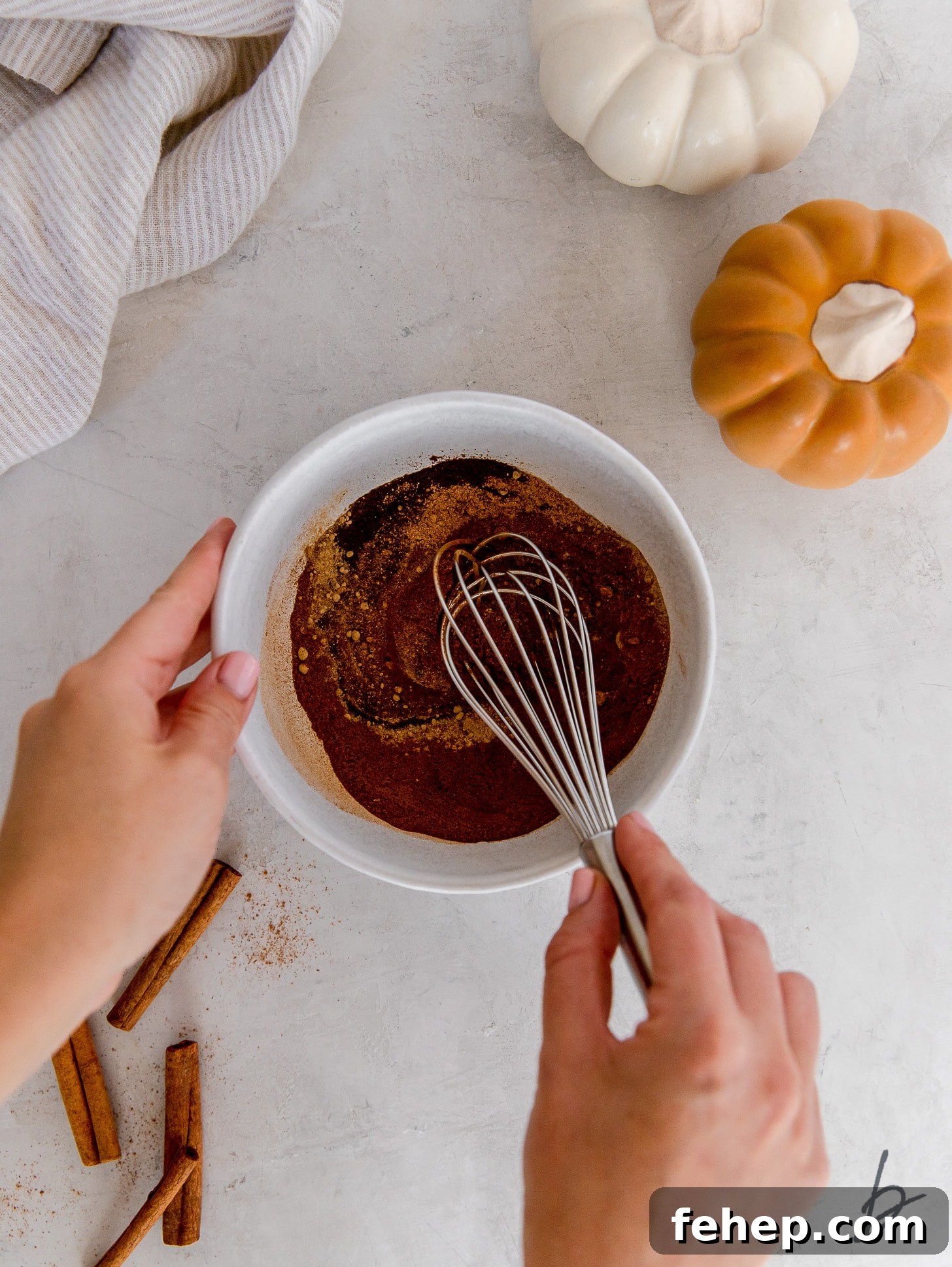 hand holding whisk combining pumpkin pie spices in a bowl