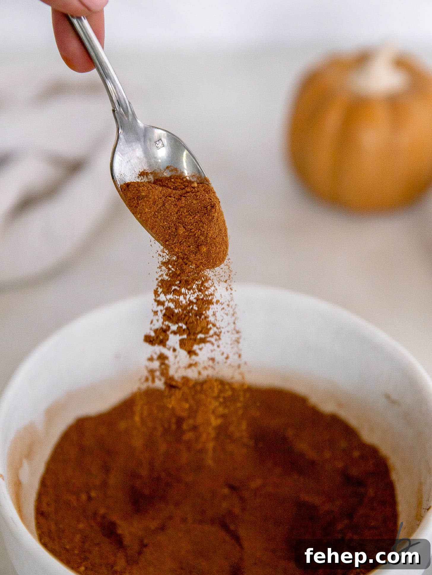 spoon sprinkling pumpkin pie spice into bowl