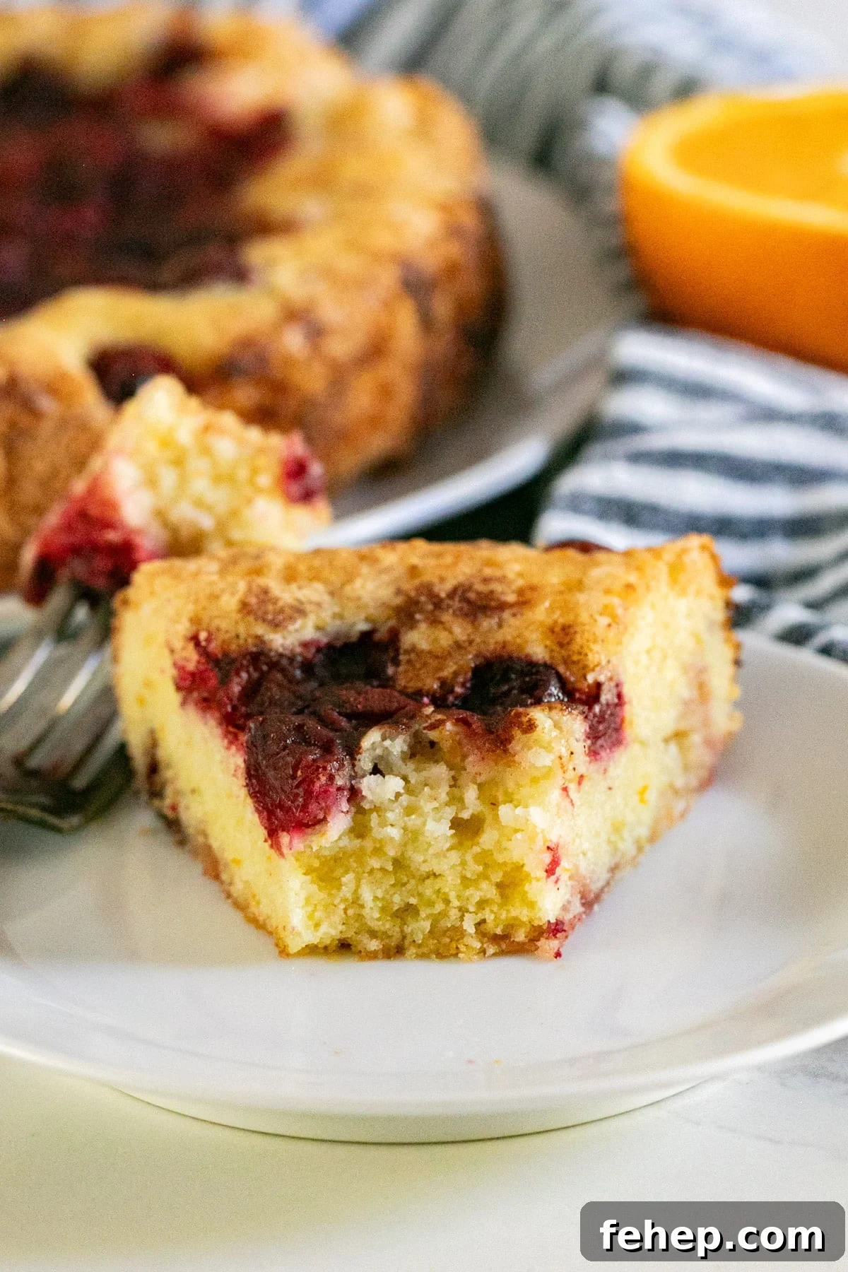 Moist Orange Cranberry Cake Recipe with Zesty Glaze 10 A slice of cake with the front bite removed revealing the interior.