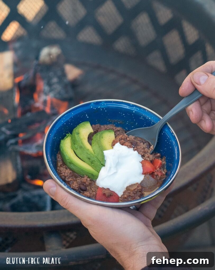 Gluten-Free Camping Meal Ideas for Delicious Outdoor Cooking 5 a spoon dipping into chilli next to a camp fire