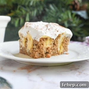Creamy Eggnog Poke Cake Recipe for Holiday Gatherings 10 piece of eggnog poke cake on a plate in front of greenery and a baking pan.