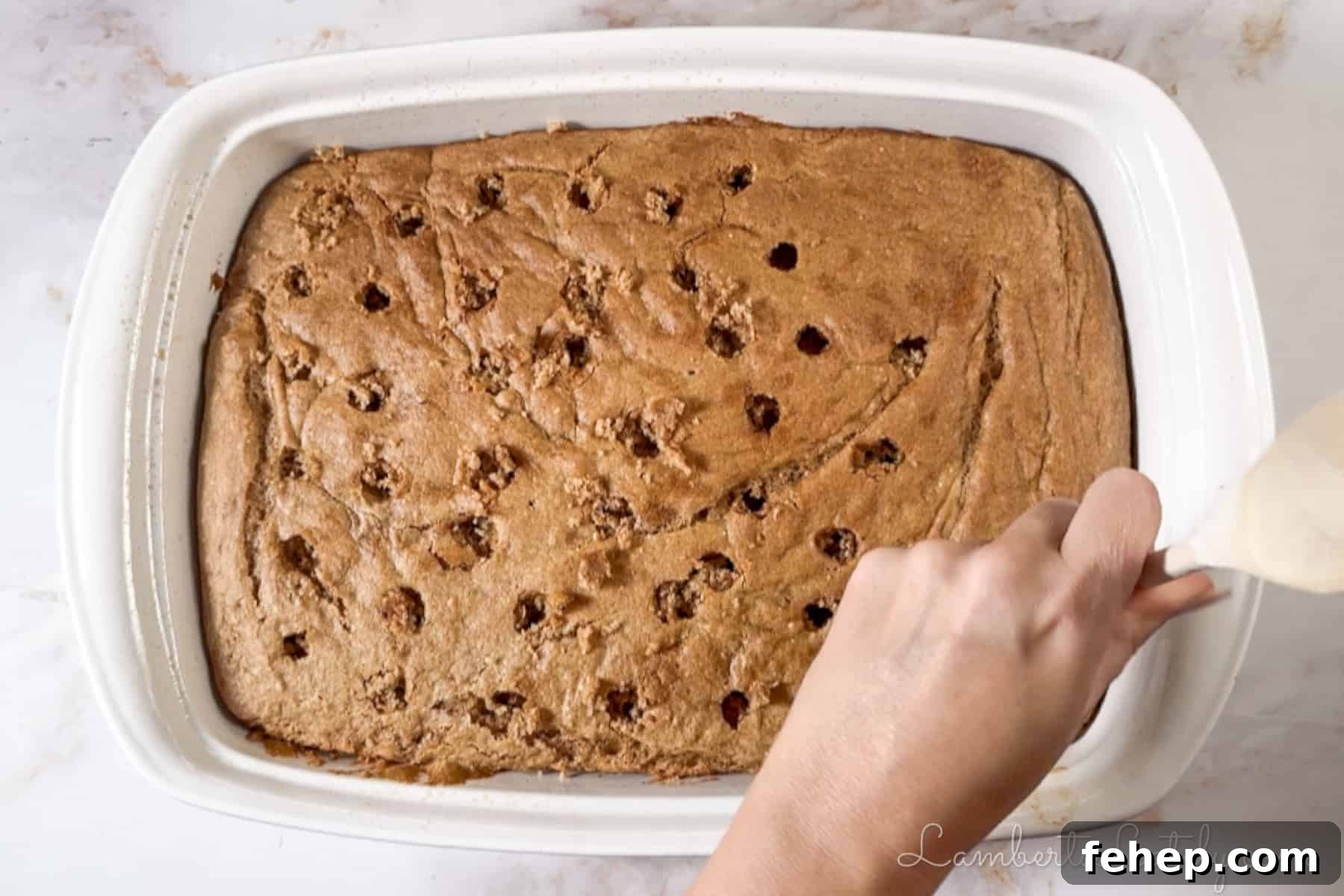 Creamy Eggnog Poke Cake Recipe for Holiday Gatherings 5 poking holes in a baked spice cake with the back of a wooden spoon.