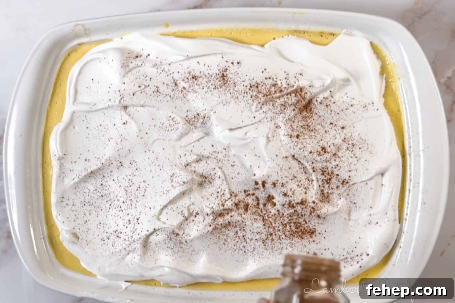 Creamy Eggnog Poke Cake Recipe for Holiday Gatherings 7 sprinkling cinnamon on top of the finished cake.