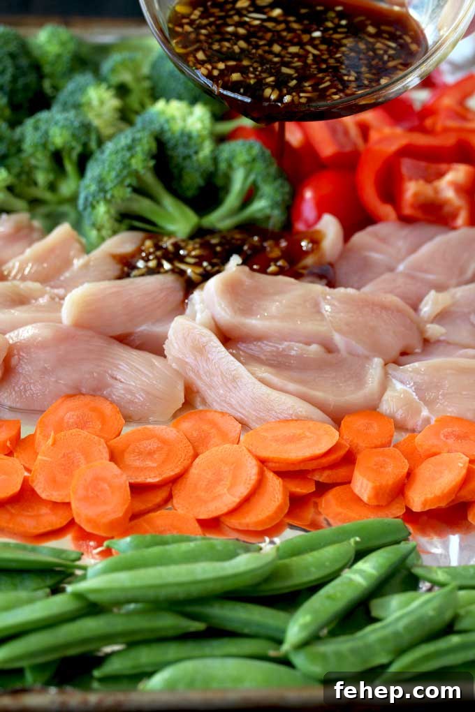 Sheet Pan Chicken and Vegetable Stir-Fry Recipe for Quick Dinners 4 Pictured here a small bowl with stir fry sauce is been poured over a sheet pan with ingredients to make this easy Asian Chicken and Vegetables Stir Fry. Raw chicken, sliced carrots, red bell peppers, broccoli florets and sugar snap peas.