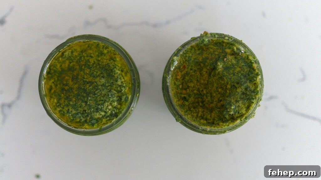 Two jars of basil pesto: The one on the left used raw pine nuts, and the one on the right used toasted pine nuts. There are deeper brown and yellow specks in the jar on the right, attributing to greater flavor.