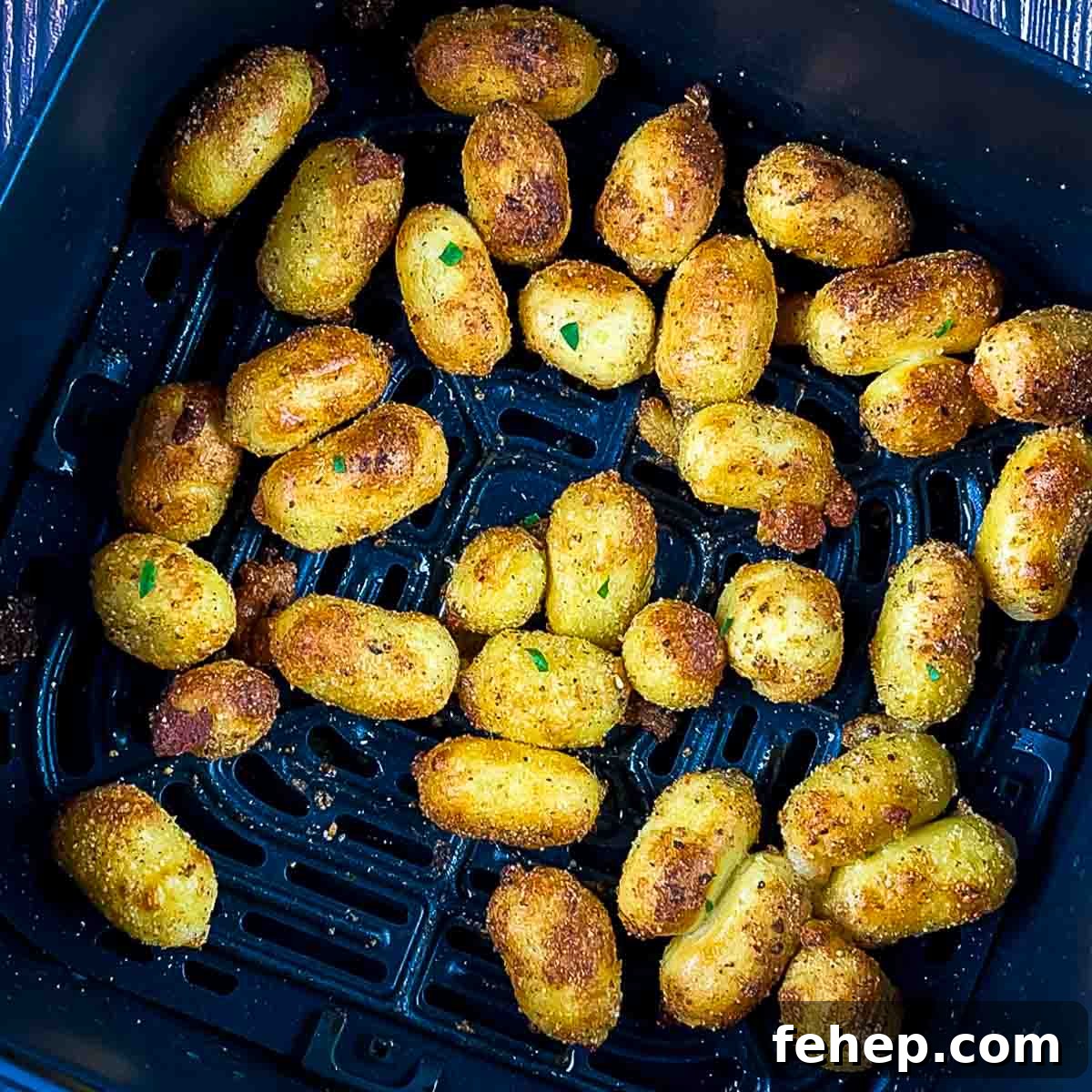 Crispy Air-Fried Gnocchi with Garlic Parmesan Crunch 8 Crispy Italian dumplings garnished with parsley in the air fryer basket.