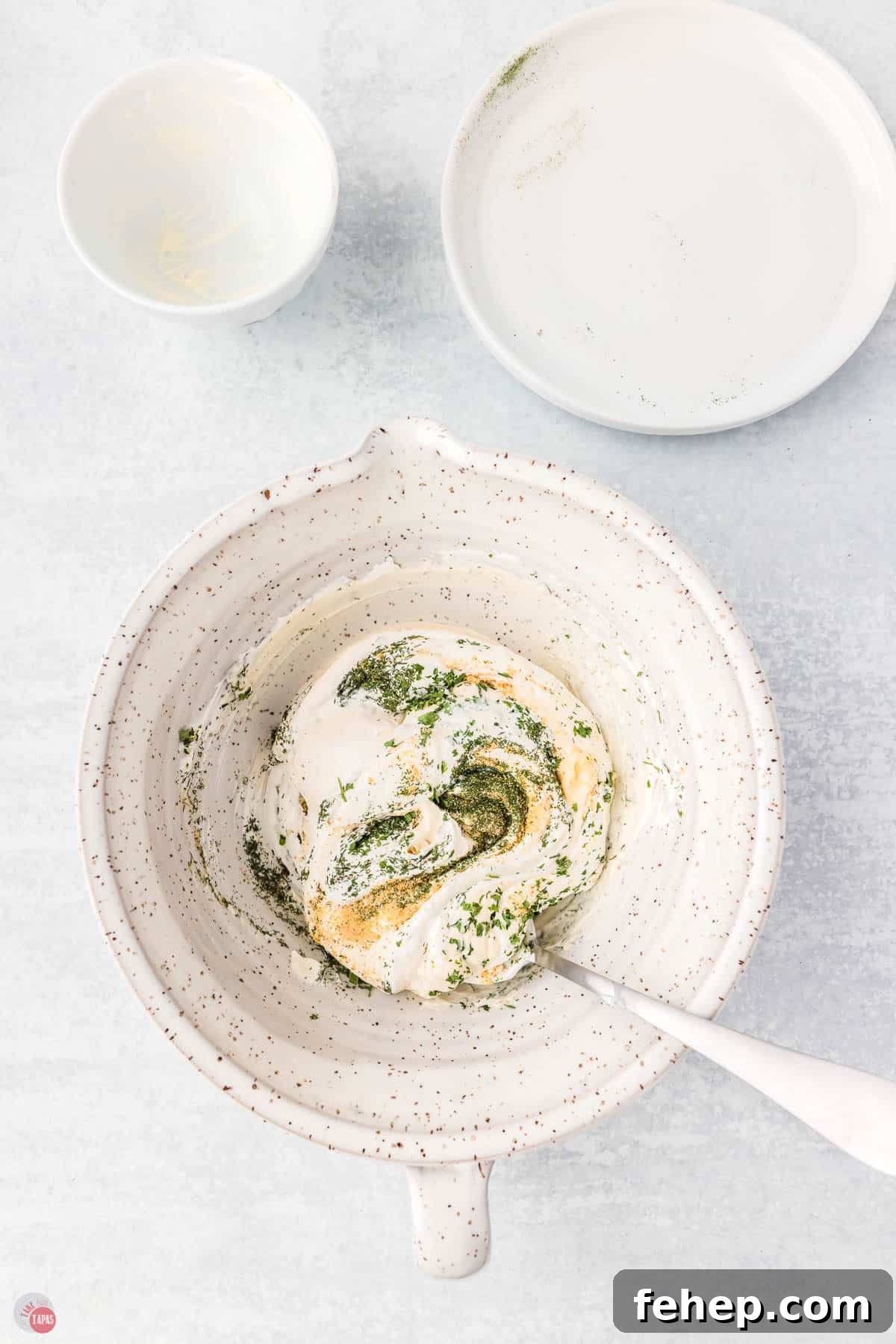 white bowl with sour cream and spices being mixed together with a spoon