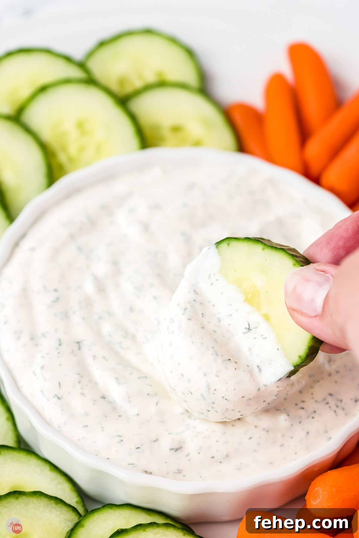 creamy dip in a white bowl with carrots and cucumbers