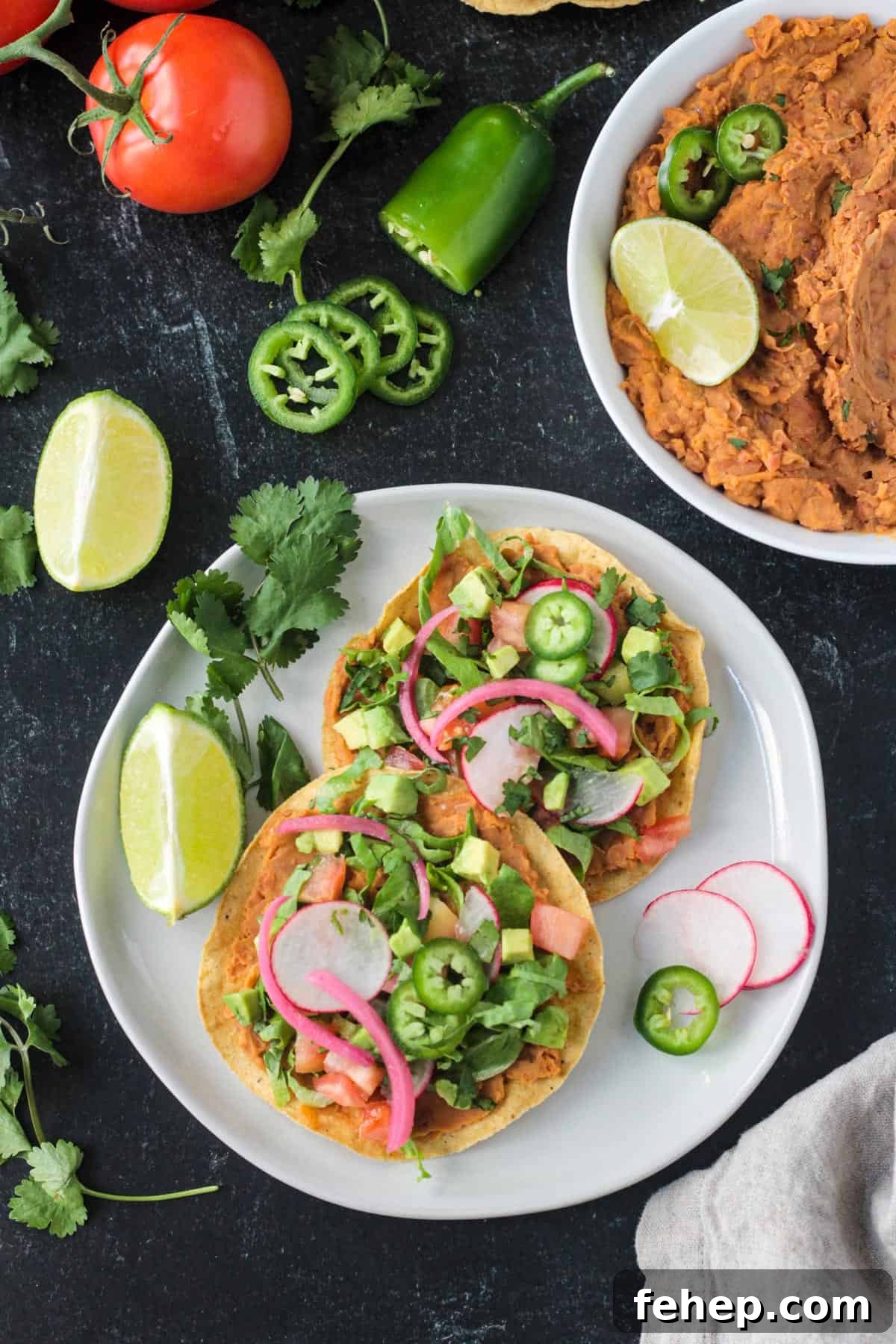 Vegan tostadas with refried beans and lots of toppings on a plate.