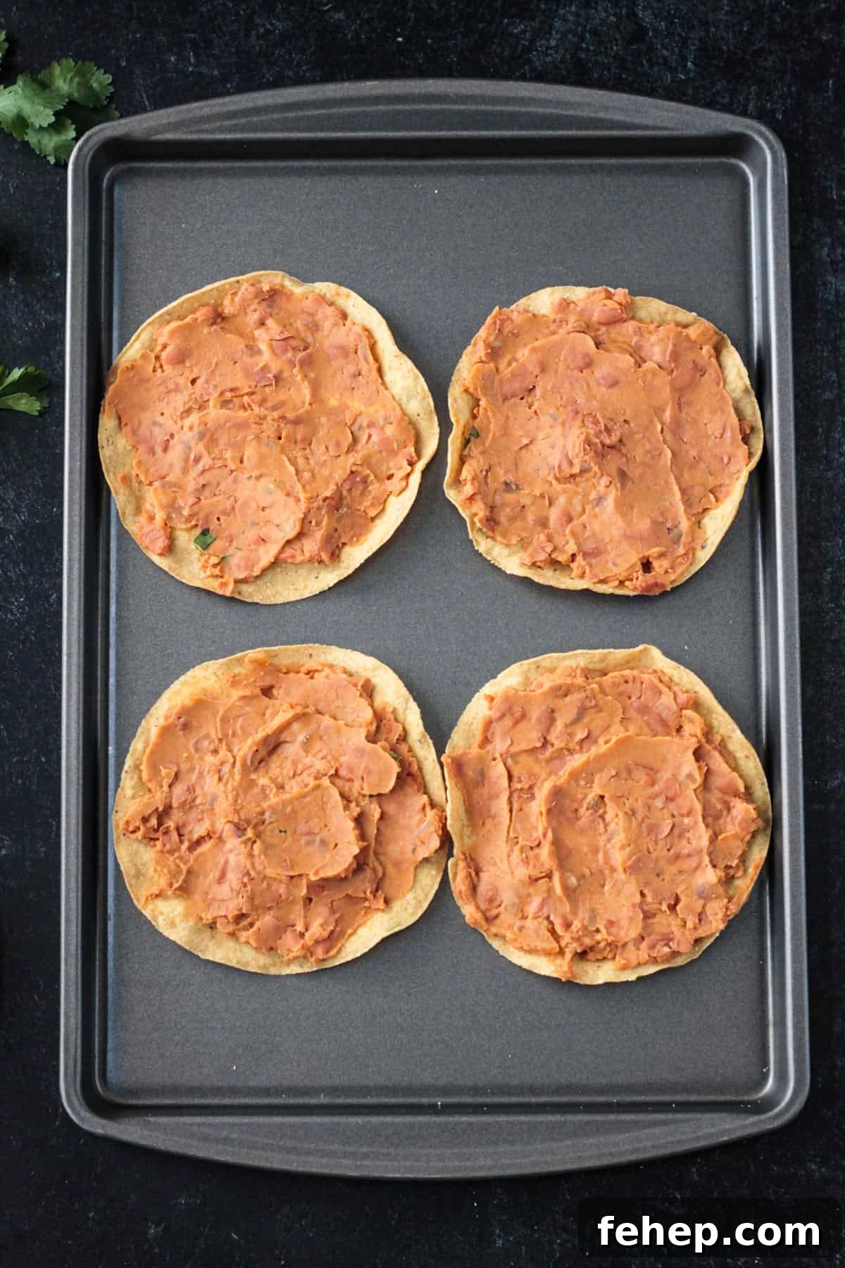 Refried beans spread on 4 tostada shells.