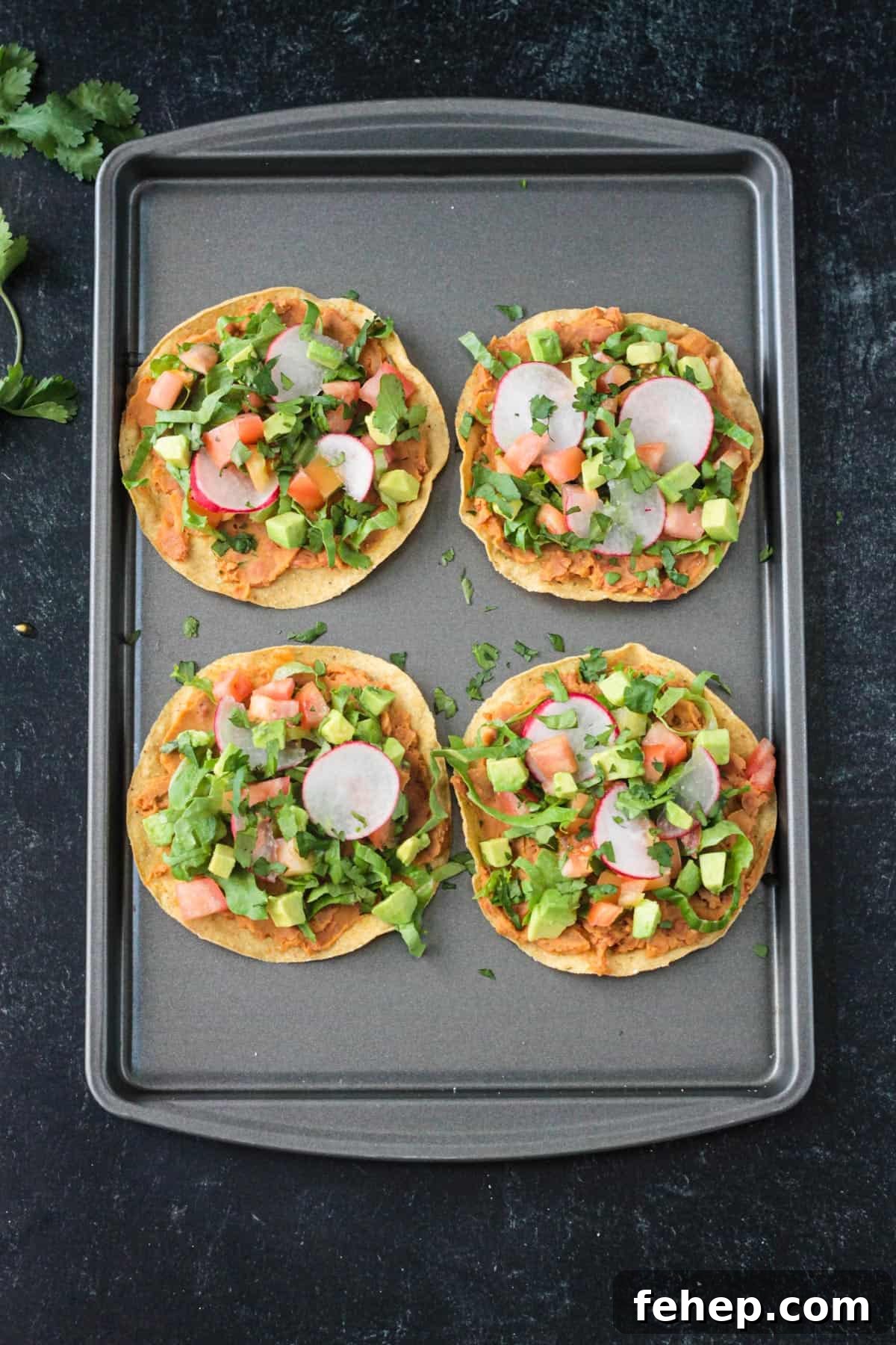 4 crispy corn tortillas topped with beans, lettuce, tomato, avocado, and cilantro.