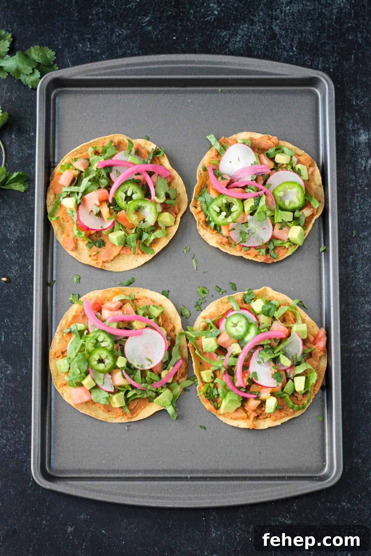 4 crispy corn tortillas topped with beans, lettuce, tomato, avocado, radishes, and onion.