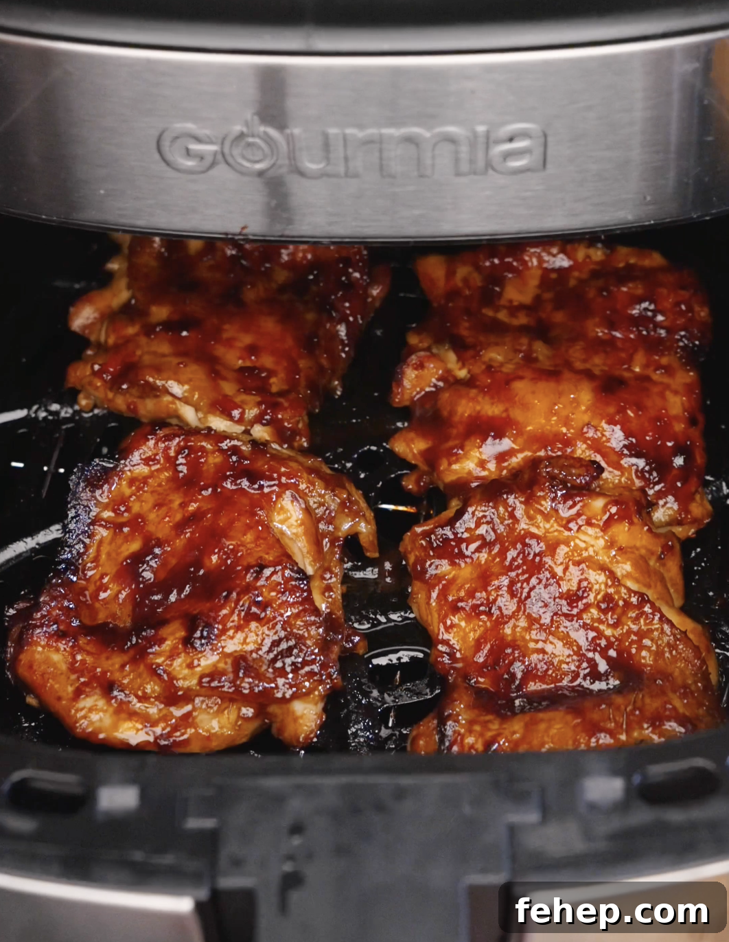 Marinated chicken thighs caramelizing inside an air fryer basket while cooking Sweet Chili Chicken.