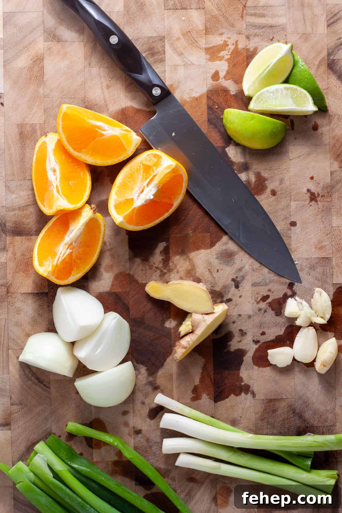 Ginger Citrus Soy Chicken with Spicy Sesame Glaze 4 Scallions, ginger, garlic, orange, lime and onion chopped up on a cutting board.