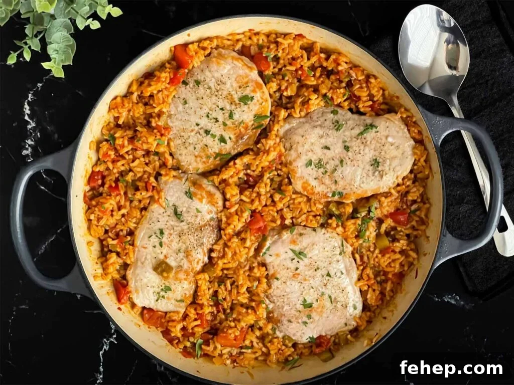 Spanish-Style Pork Chops with Garlic Tomato Rice 2 Spanish pork chops and rice garnished with chopped parsley in a light colored skillet.
