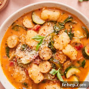 italian sausage and gnocchi soup in a white bowl with a spoon