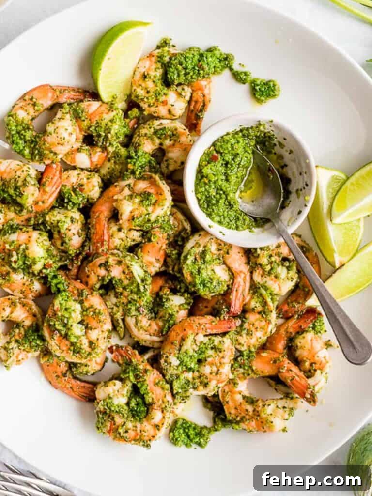 cilantro lime shrimp with lime wedges and extra sauce in a small bowl with a spoon