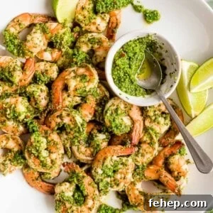 cilantro lime shrimp with lime wedges and extra sauce in a small bowl with a spoon