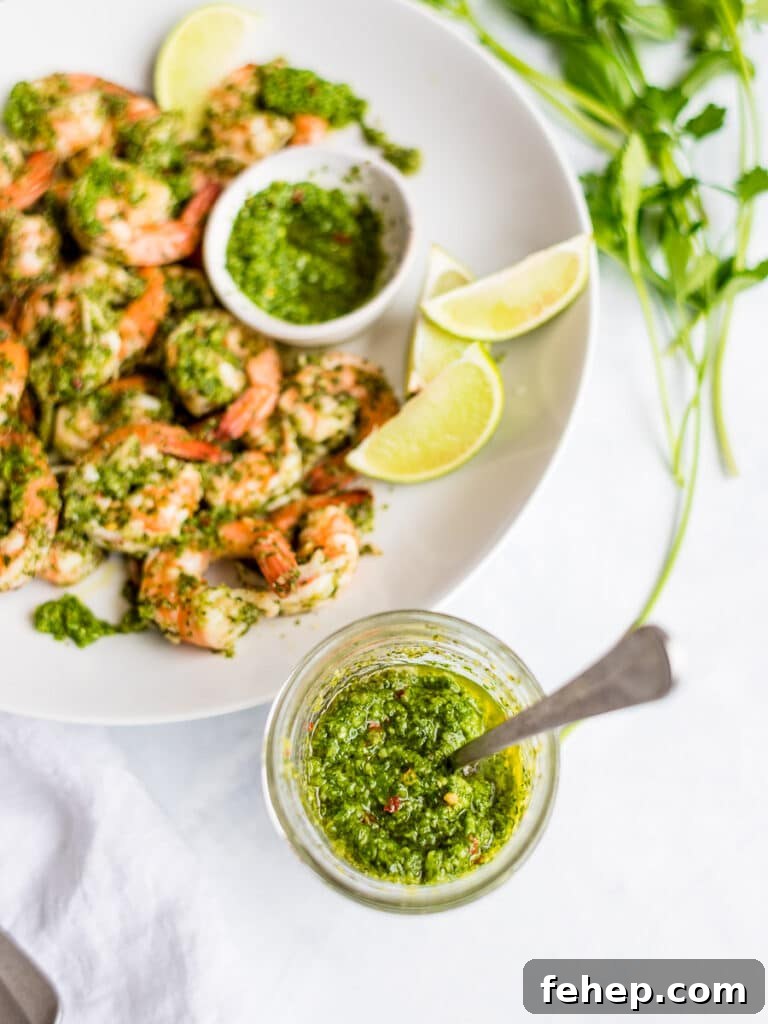 cilantro lime sauce in a mason jar with cilantro lime shrimp on a white plate