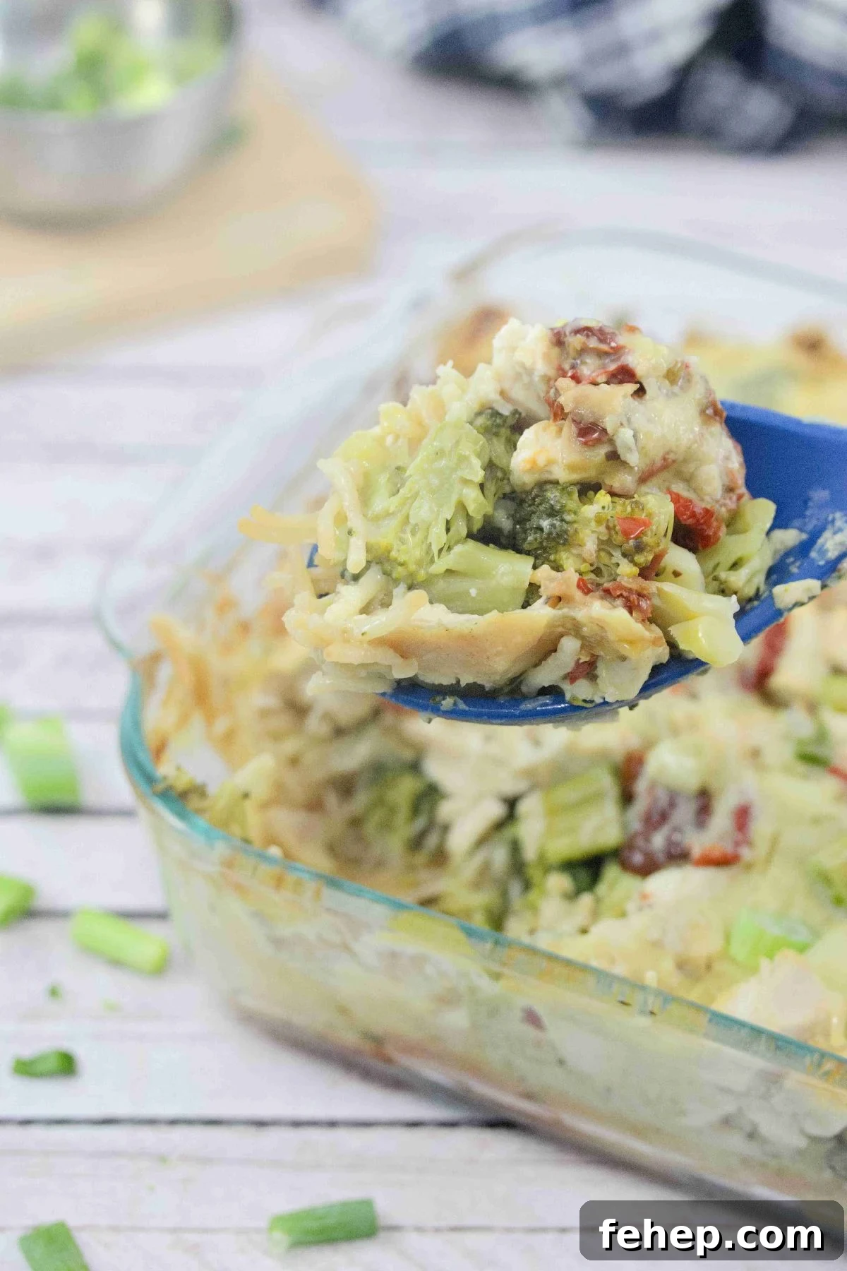 Gluten-Free Dairy-Free Chicken Alfredo Casserole Recipe 2 Dairy-free chicken alfredo casserole in a clear casserole dish with green onions on top and a blue spoon scopping some out.