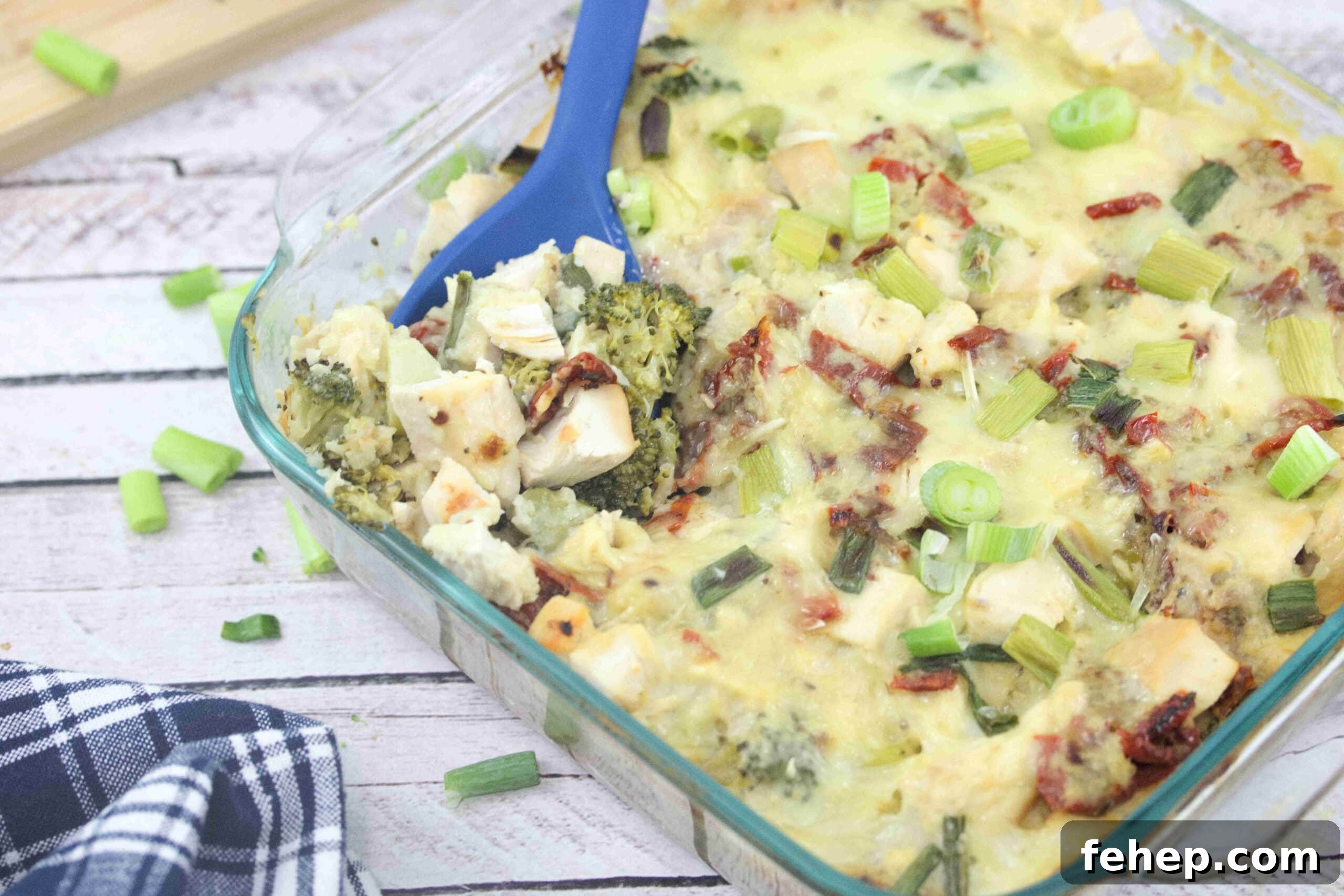 Gluten-Free Dairy-Free Chicken Alfredo Casserole Recipe 14 Dairy-free chicken alfredo casserole in a clear casserole dish with green onions on top and a blue spoon scopping some out.