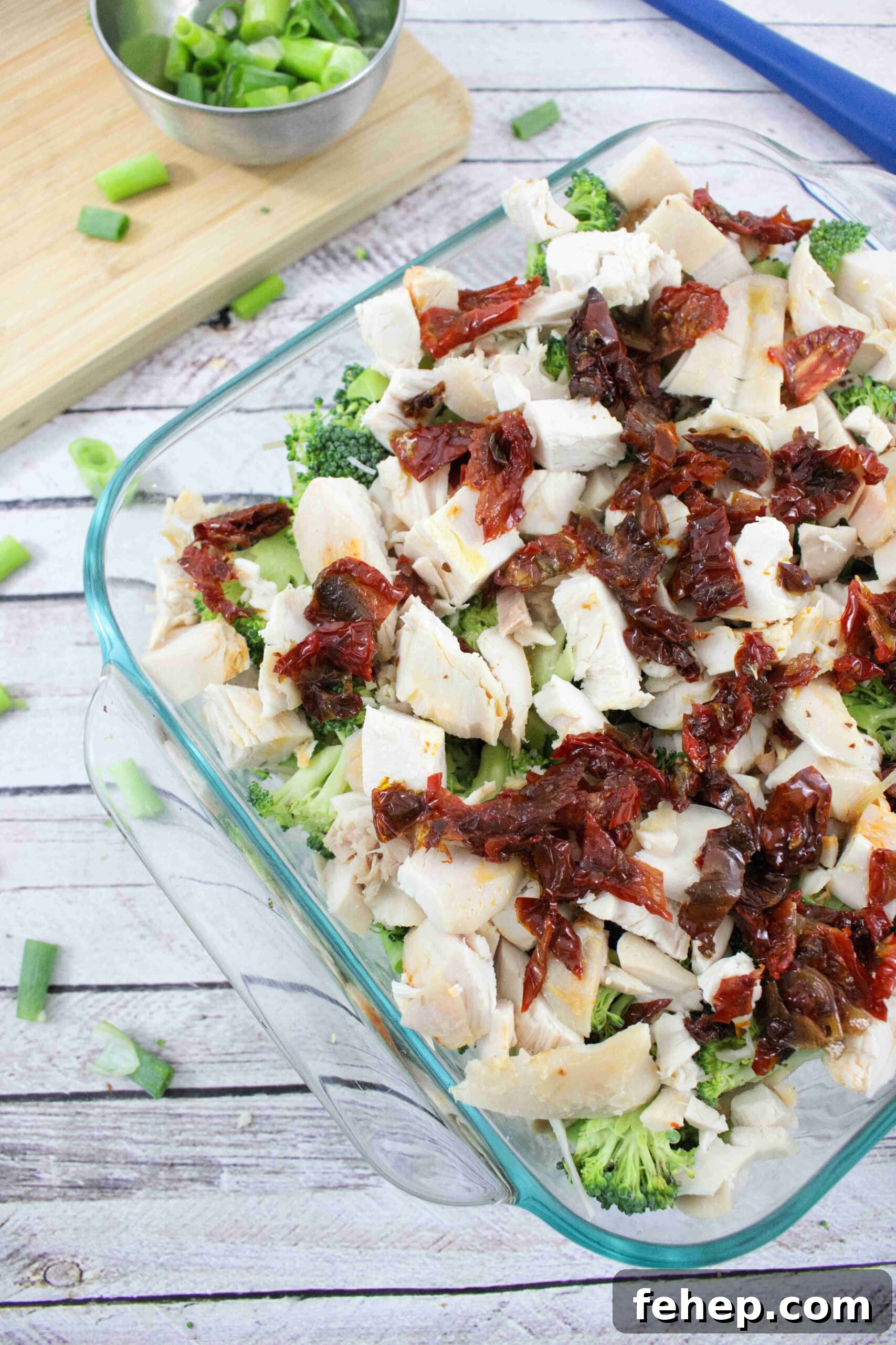 Gluten-Free Dairy-Free Chicken Alfredo Casserole Recipe 5 Clear casserole dish with chicken, broccoli, and sundried tomatoes in it.