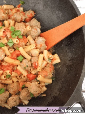 Cast iron pan with tomato and sausage pasta on gluten-free noodles