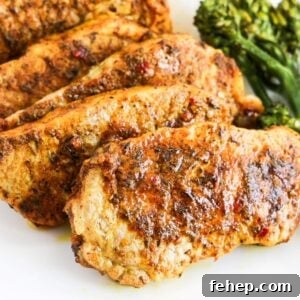 Five cooked jerk lime boneless pork chops overlapping each other one a white plate with broccoli to the right.