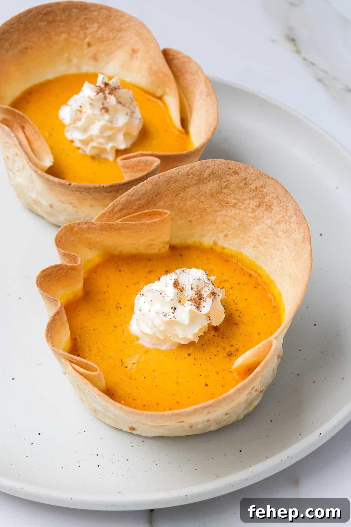 Side shot of pumpkin pies with whipped cream.