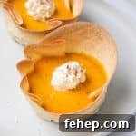Side shot of pumpkin pies with whipped cream.