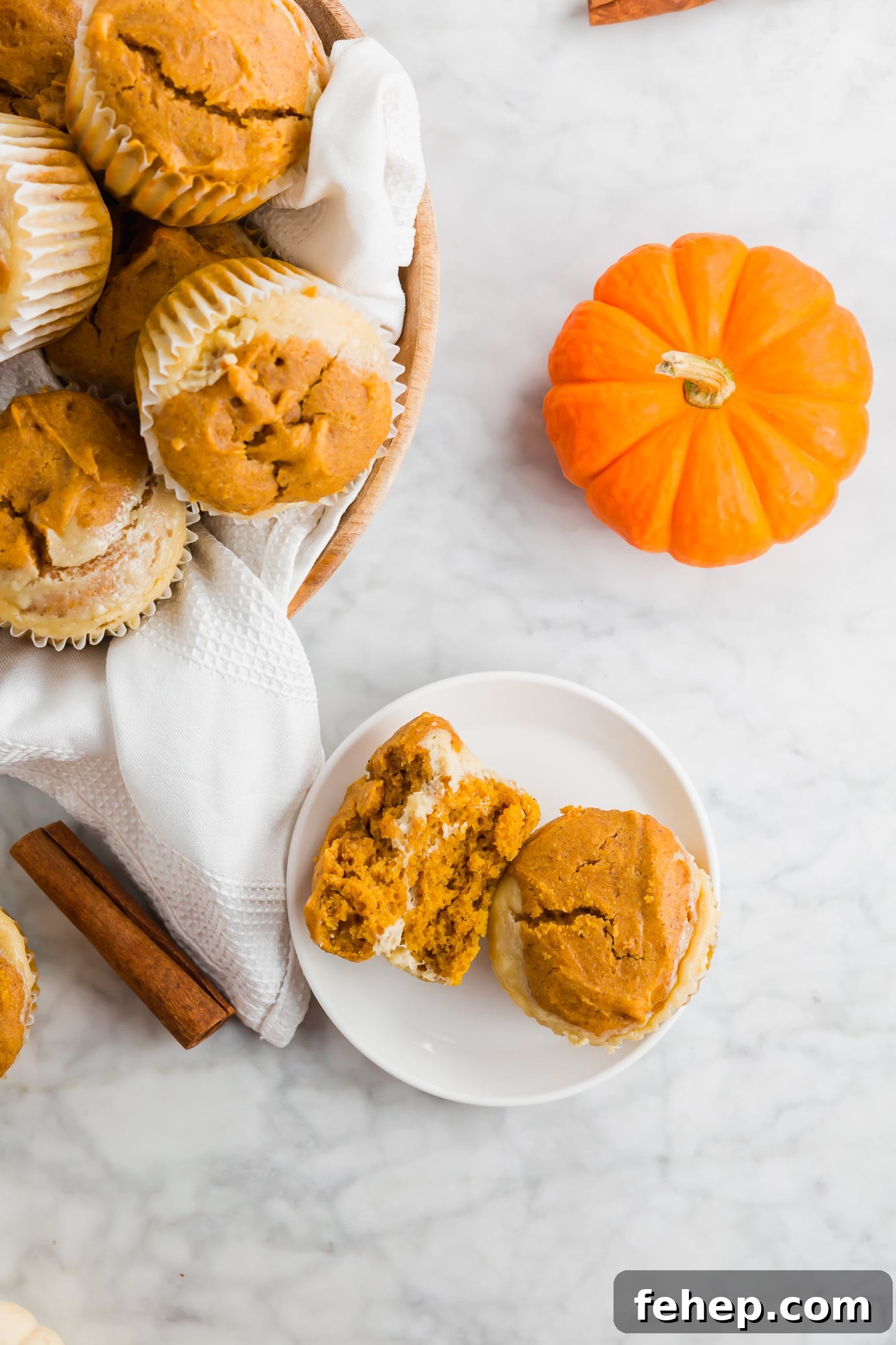 Pumpkin Cheesecake Muffin Cross-Section A photo of a pumpkin cheesecake muffin split in half on a plate.