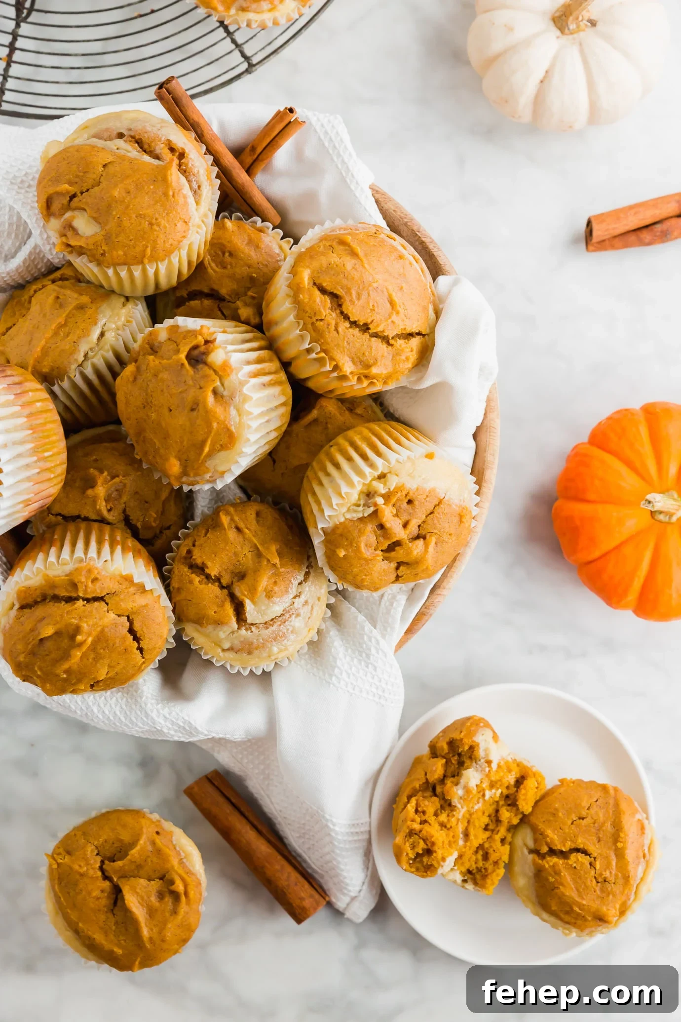 Gluten-Free Pumpkin Cream Cheese Muffins Recipe for Fall 3 A basket of gluten-free pumpkin cream cheese muffins with fresh pumpkins and cinnamon sticks.