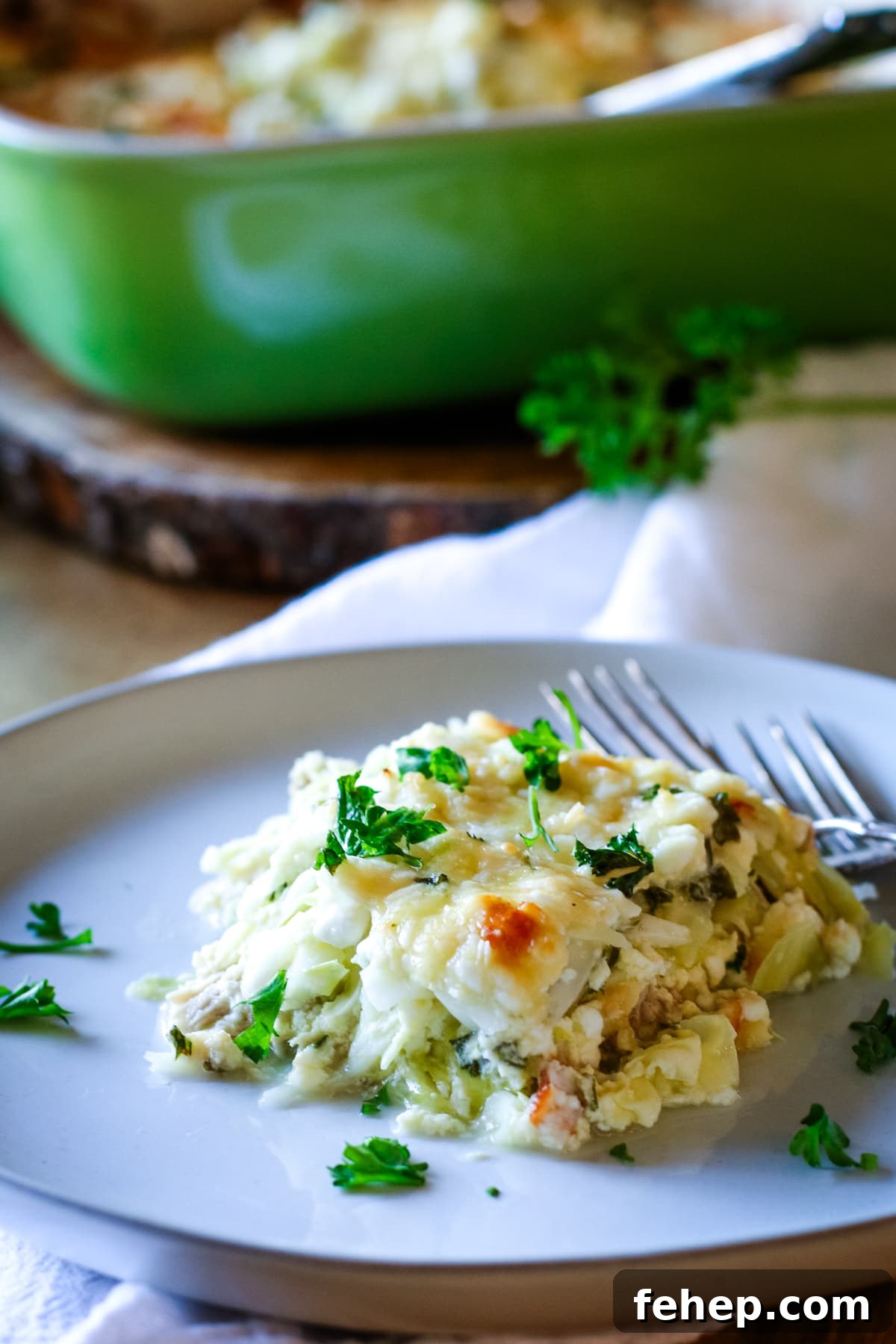 chicken cabbage bake on a white plate with green pan in the background.