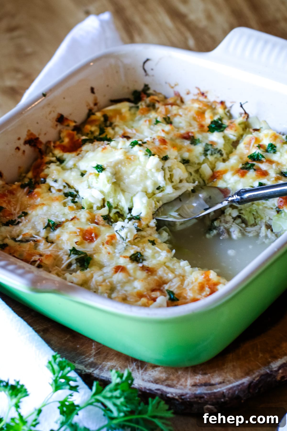 chicken cabbage casserole in a green casserole dish with spatula.