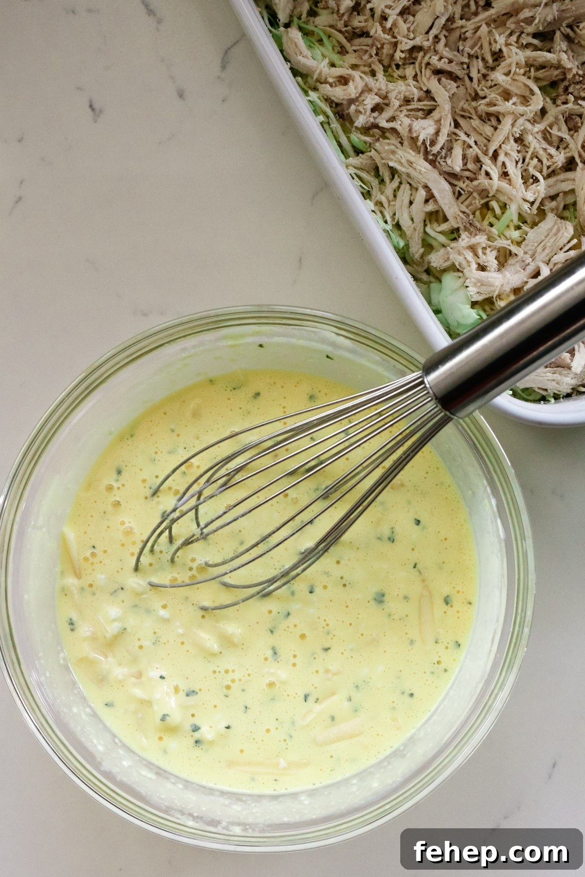 eggs and cottage cheese mixture with a whisk in a clear bowl.