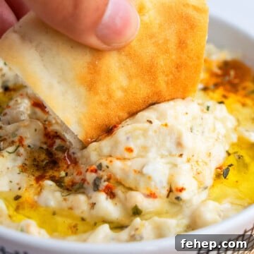 Pita Bread Being Dipped in Baba Ganoush Eggplant Dip in White Bowl- Closeup Shot.